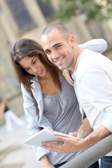 Young couple using electronic tablet in town