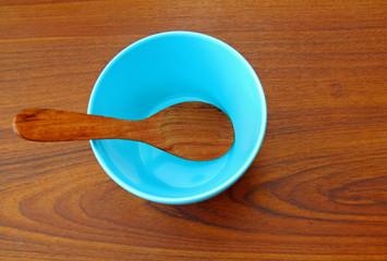 Wooden spoon in blue bowl on wood background