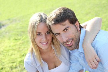 Happy young couple sitting in yard