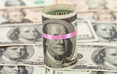100 US dollar wrapped by ribbon on money background