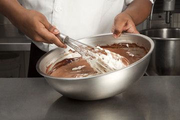 Cuisinier mélangeant des blancs en neige et du chocolat fondu