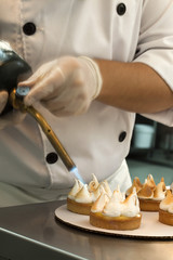 Cuisinier brûlant la meringue des tartelettes au fer