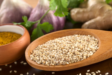 Raw sesame seeds on wooden spoon