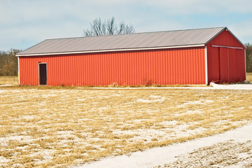 Red siding barn in the winter after a snow fall