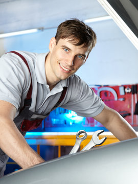 Handsome motor mechanic is happy with his job in a garage