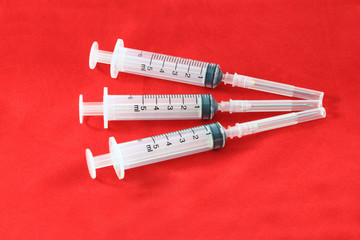 Three hypodermic syringe on red velvet for first aid kids.