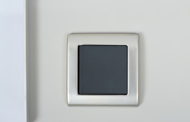 light switch on the wall with grey button on silver frame