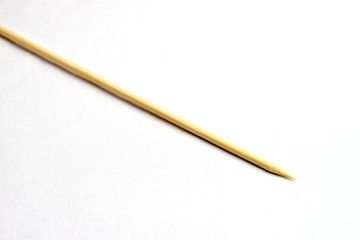 Single wooden bamboo skewer laying on white background