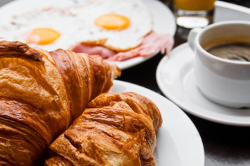 Breakfast with coffee and croissants in a basket on table