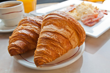 Breakfast with coffee and croissants in a basket on table