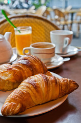 Breakfast with coffee and croissants in a basket on table