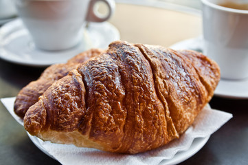 Breakfast with coffee and croissants in a basket on table