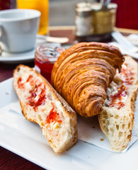 Breakfast with coffee and croissants in a basket on table