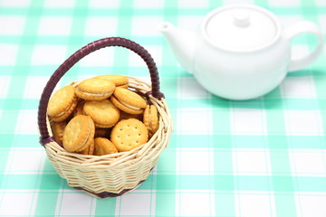 籠に入れたビスケットサンドとティーポット