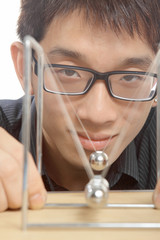 man moving Newton balls in office