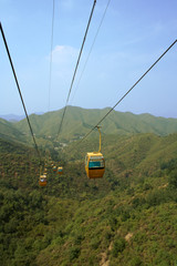 Cable cars traversing climb over green hills in summer