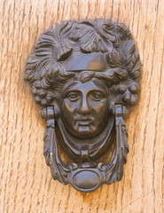 Medieval bronze knocker on the wooden door