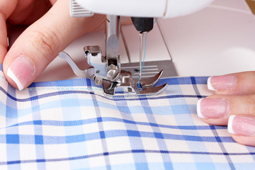 sewing machine, blue fabric and women's hands