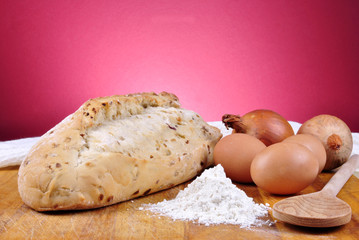 Zwiebelbrot auf einem Holzbrett mit Backzutaten