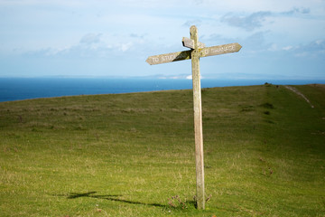 Wooden cross footpath sign with directions to Studland / Swanage