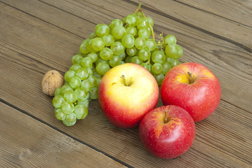 apples , nut and grapes on wooden table