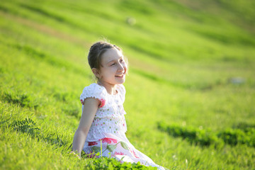Fototapeta na wymiar Girl sits on a grass