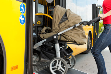 Frau mit Kinderwagen steigt in Bus ein