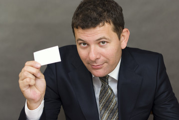 Business man handing a blank business card over gray background