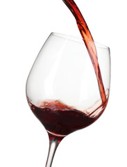 Red wine pouring into glass isolated on white