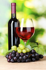 Ripe grapes and glass of wine on green background