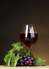 Glass of wine and grapes on yellow background