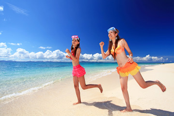 砂浜の上を走る二人の女性