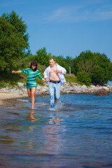 Enamored couple running along the coast of sea