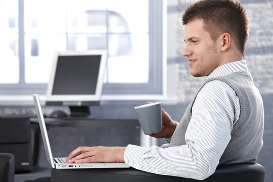 Young man working in office using laptop