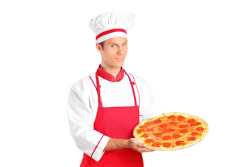 A studio shot of a young chef holding a pizza