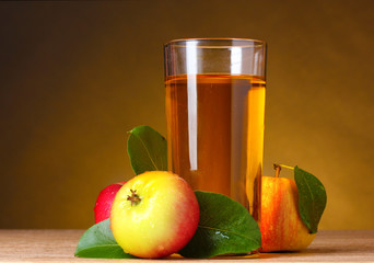 Apple juice and apples on wooden table on brown background