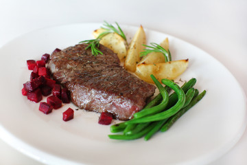 Sirloin with beetroot, beans and potatoes with rosemary on white