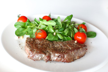 Sirloin steak with fresh corn salad and cherry tomatoes on white