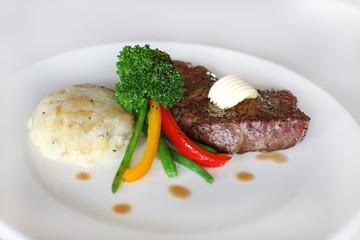 Sirloin steak with potatoes and fried vegetables on white