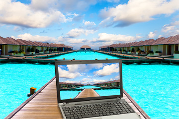 Wooden road  over the sea and the laptop with a beach picture..