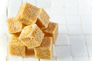Cubes of not refined reed sugar lie on pieces of white sugar
