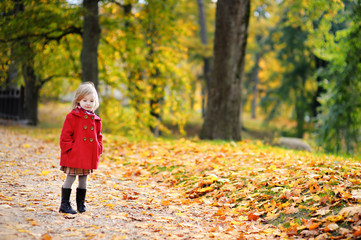 Little girl in a red coat at autumn