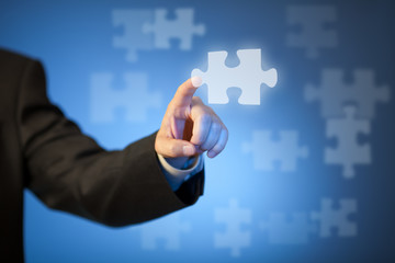 Businessman's hand touching abstract puzzle piece