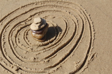Fototapeta na wymiar Stones pyramid at the beach, circles in the sand