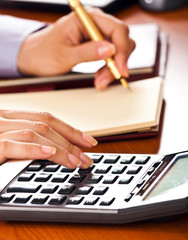 Businesswoman accounting on her agenda, using a calculator