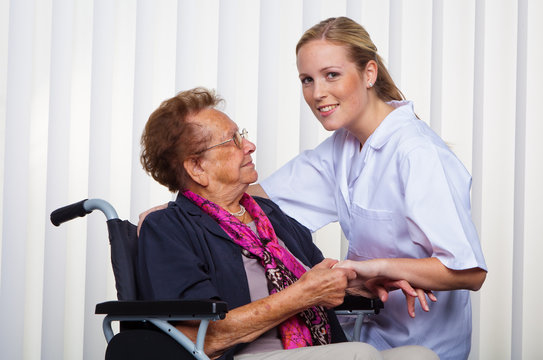Krankenpflegerin und alte Frau im Rollstuhl