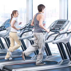 Fototapeta na wymiar Young woman and man at the gym exercising. Running