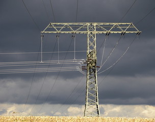 Hochspannungsmast vor dunklen Wolken