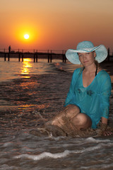 Beautiful girl on the seashore at sunset