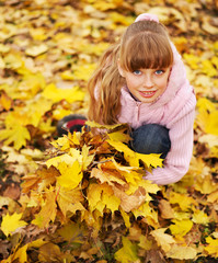 Kid in autumn orange leaves.